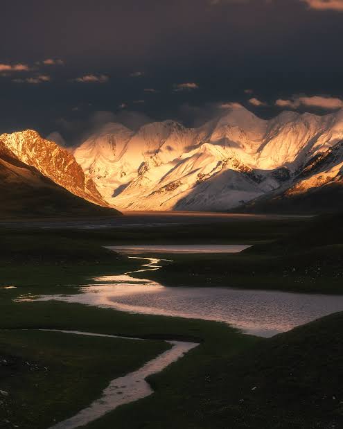 Sunset over snowy peaks with a winding mountain stream